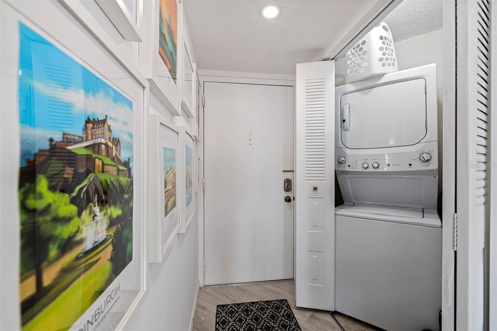 A hallway features framed wall art, a white entry door, and a stacked laundry unit — 6145 SUN BOULEVARD UNIT 304, ST PETERSBURG, FL
