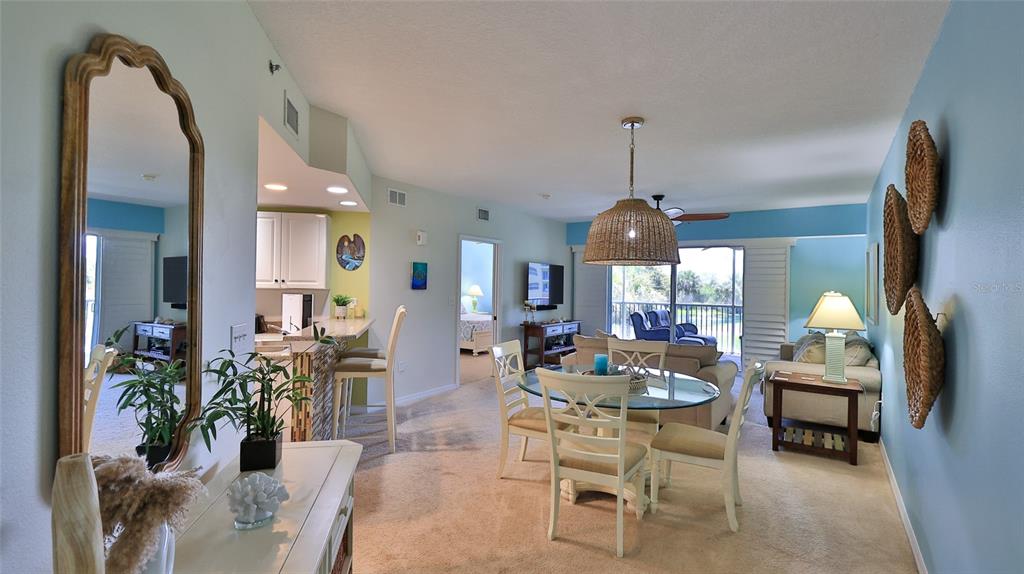 A dining area and living room feature a glass table, wicker pendant light, and balcony — 5300 S ATLANTIC AVENUE UNIT 15-202, NEW SMYRNA BEACH, FL