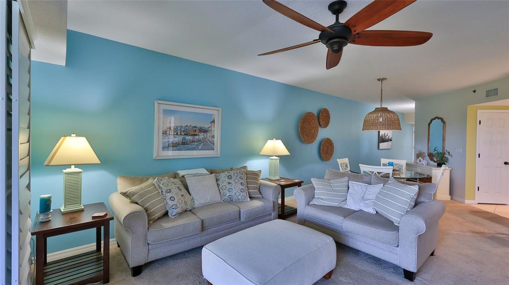 A living room features light blue walls, two gray sofas, an ottoman, and a ceiling fan — 5300 S ATLANTIC AVENUE UNIT 15-202, NEW SMYRNA BEACH, FL