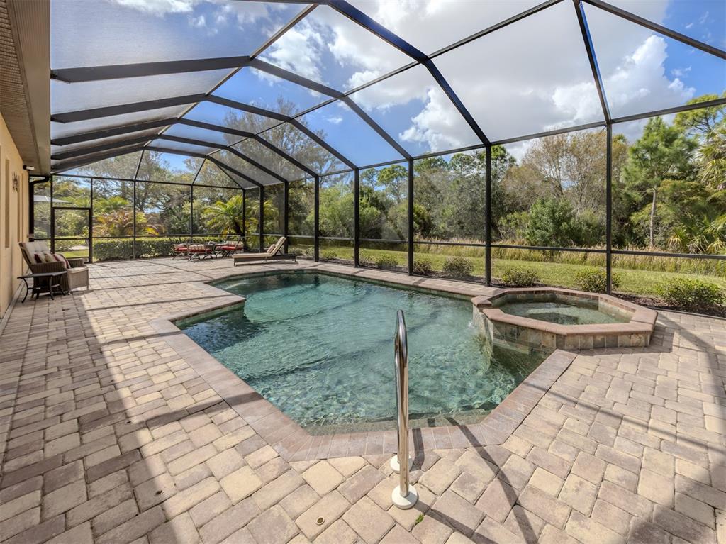 A screened-in patio features a swimming pool, a raised spa, and brick paver decking — 20925 LOGGIA COURT, VENICE, FL