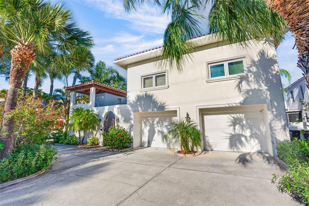 A two-story house with a white stucco exterior, two garage doors, and palm trees — 831 MANDALAY AVENUE, CLEARWATER BEACH, FL
