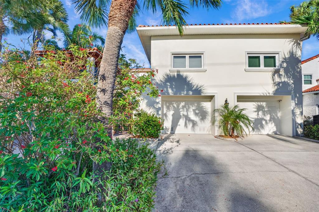A two-story house with a two-car garage, white stucco walls, and palm trees in front — 831 MANDALAY AVENUE, CLEARWATER BEACH, FL