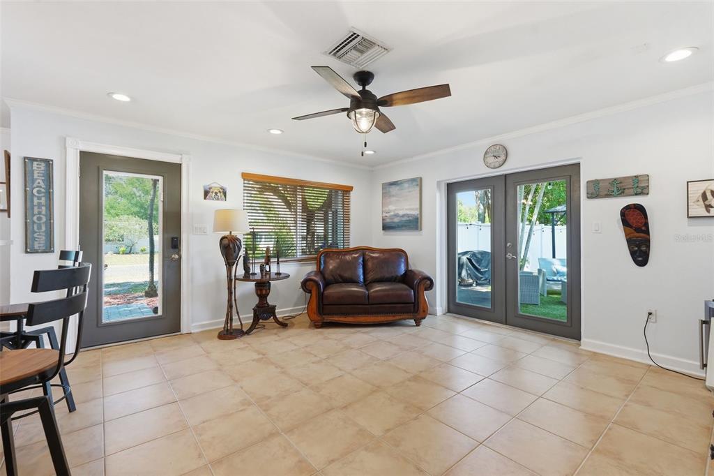 A living room with tile floors, a leather loveseat, a ceiling fan, and glass doors — 961 LEXINGTON DRIVE, DUNEDIN, FL