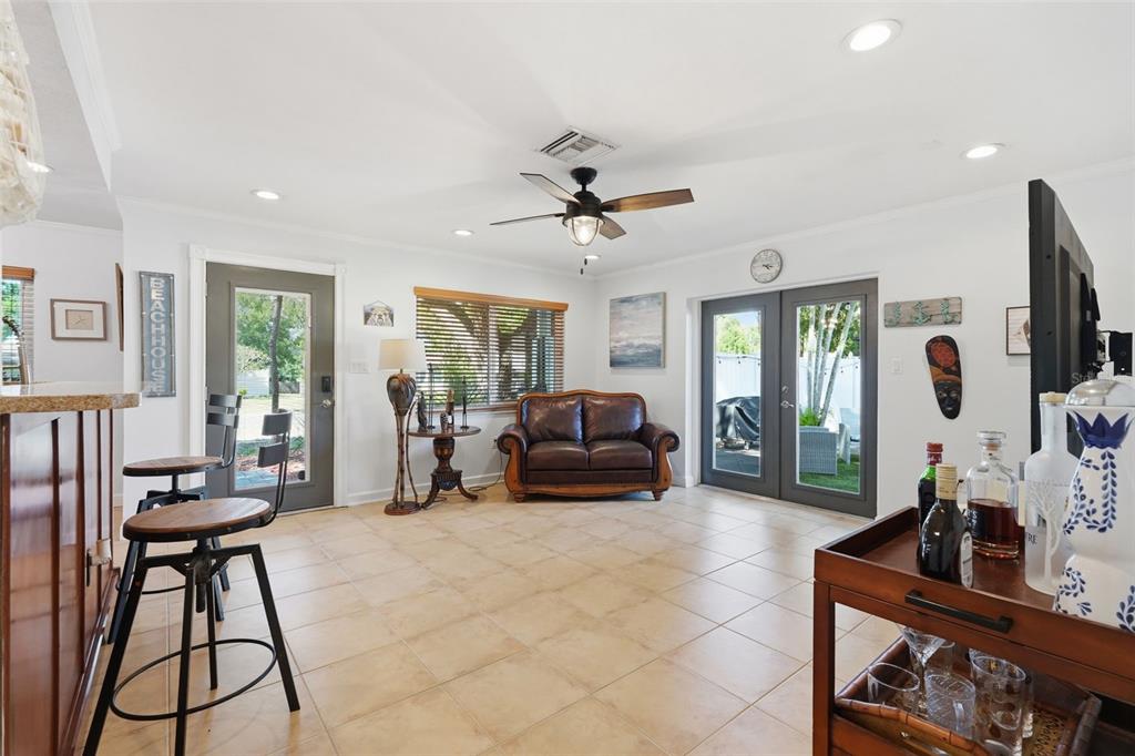 A living area features tile flooring, a leather loveseat, a ceiling fan, and glass doors — 961 LEXINGTON DRIVE, DUNEDIN, FL