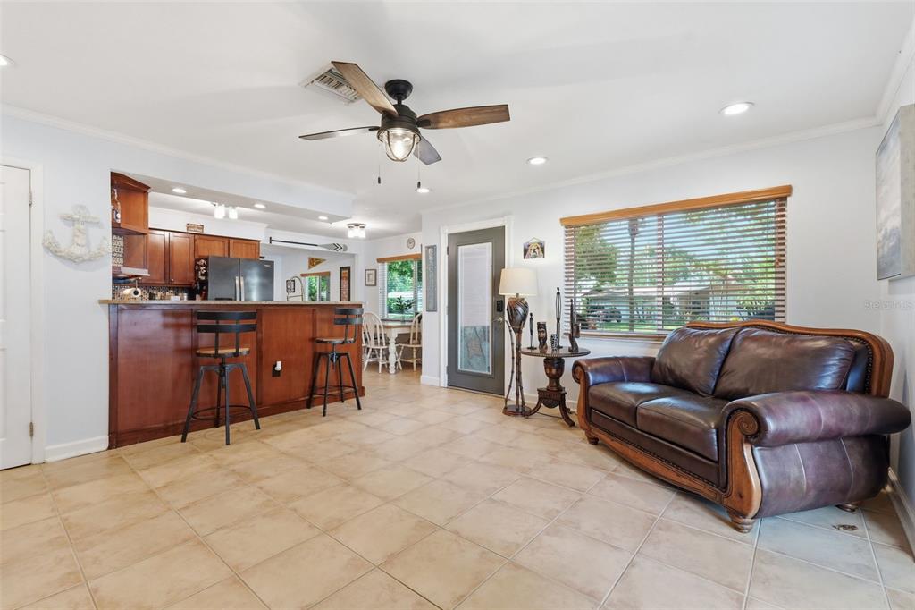 A living room features tile flooring, a leather sofa, and a kitchen breakfast bar — 961 LEXINGTON DRIVE, DUNEDIN, FL