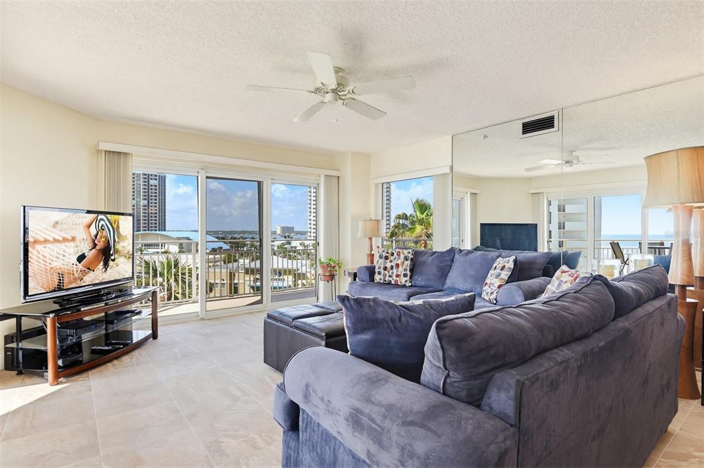 A living room features a blue sectional sofa, a television, and a balcony with ocean views — 2967 S ATLANTIC AVENUE UNIT 408, DAYTONA BEACH SHORES, FL
