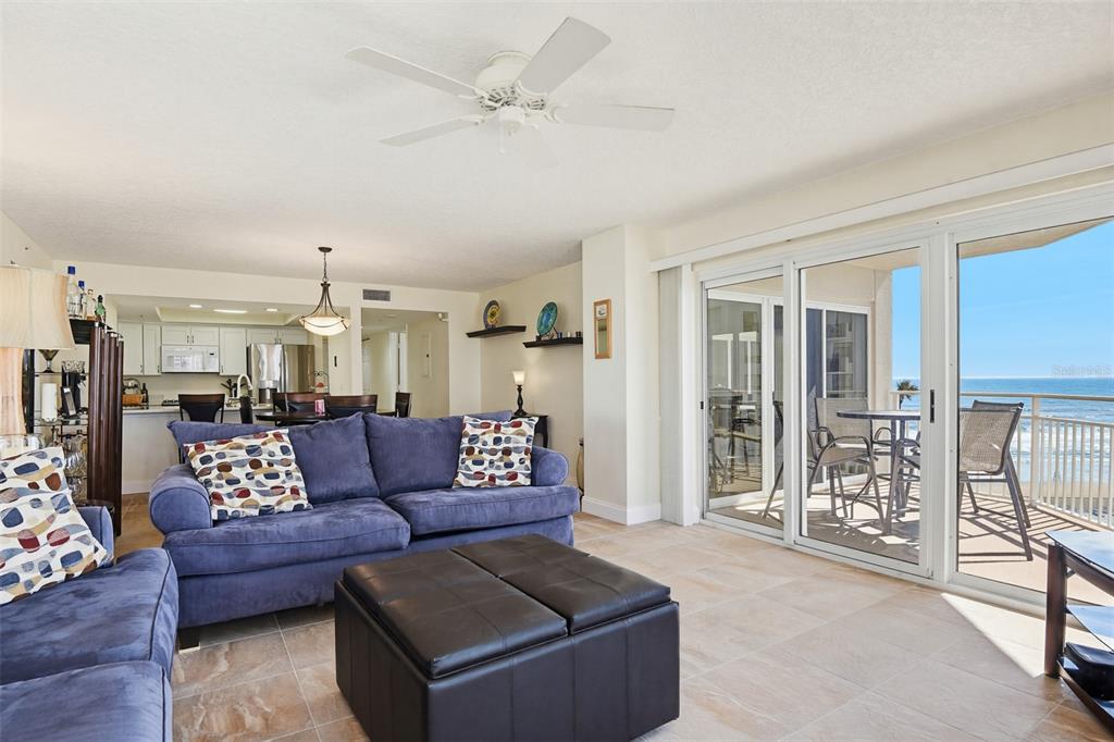 A living room with a blue sofa, tile floors, and a balcony overlooking the ocean — 2967 S ATLANTIC AVENUE UNIT 408, DAYTONA BEACH SHORES, FL