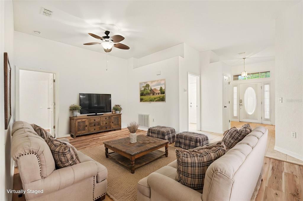 A living room with light-colored sofas, a wooden coffee table, and a television on a console — 31331 SATINLEAF RUN, BROOKSVILLE, FL