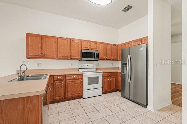 A kitchen features wood cabinets, stainless steel appliances, and tile flooring — 31331 SATINLEAF RUN, BROOKSVILLE, FL