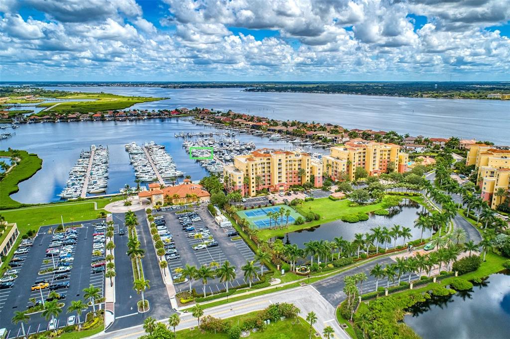An aerial view shows a marina, apartment buildings, a parking lot, and a tennis court — 102 RIVIERA DUNES WAY UNIT N57, PALMETTO, FL