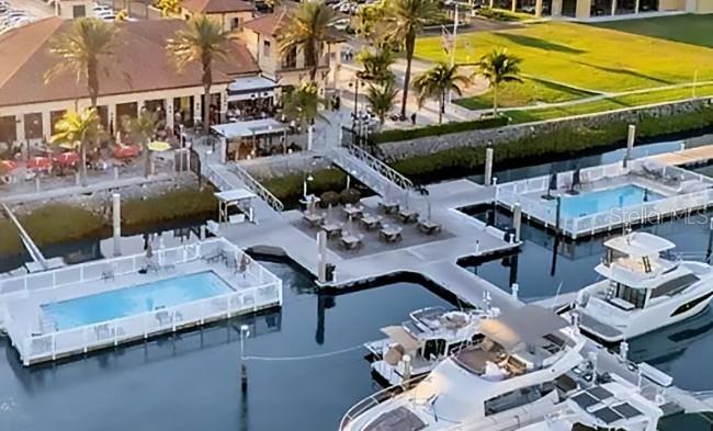 An aerial view shows a waterfront restaurant patio, two swimming pools, and docked yachts — 102 RIVIERA DUNES WAY UNIT N57, PALMETTO, FL