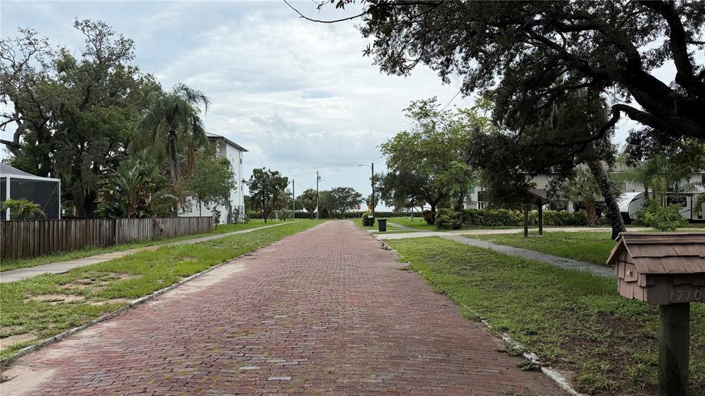 A brick-paved street leads through a neighborhood with mature trees and a wooden mailbox — TALLAHASSEE DRIVE, TARPON SPRINGS, FL