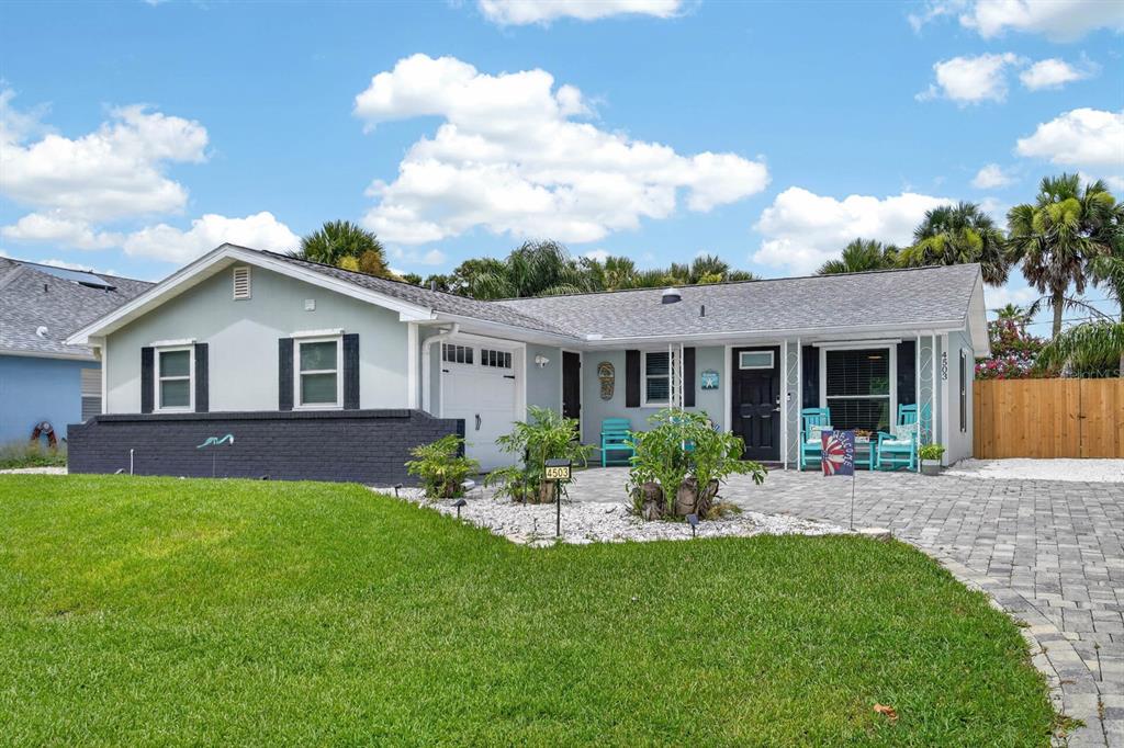 A single-story house with a light green exterior, dark brick base, and a paved driveway — 4503 SAXON DRIVE, NEW SMYRNA BEACH, FL