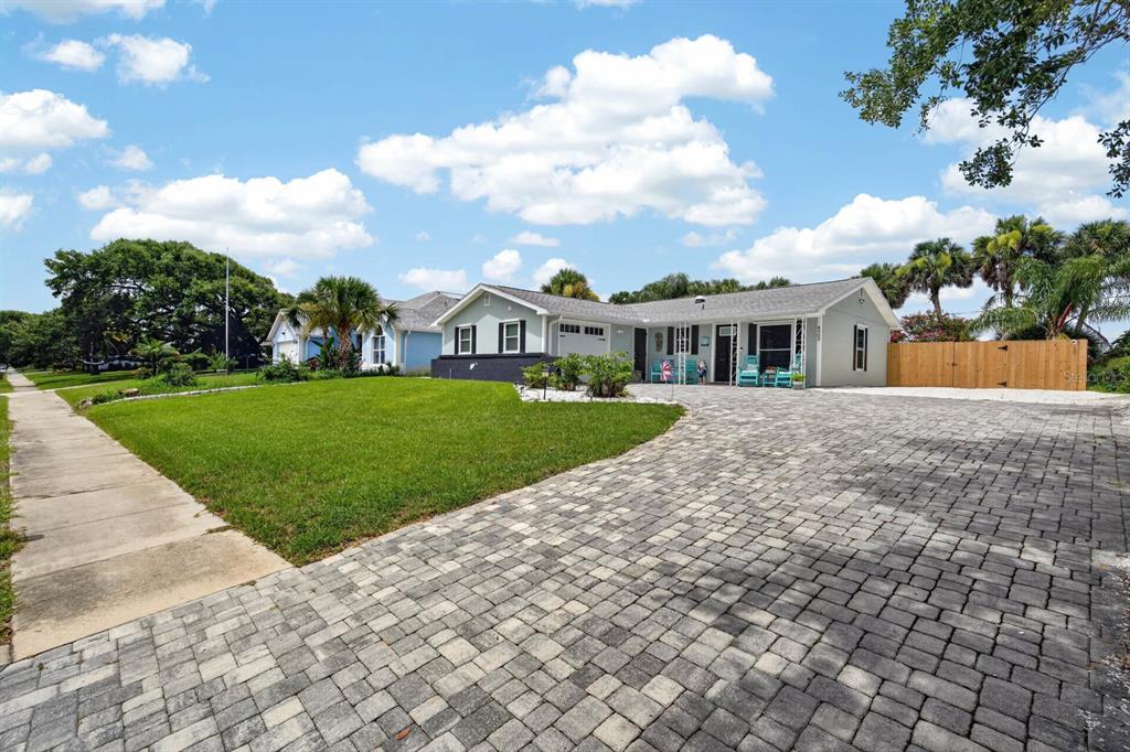 A light gray single-story house features a large paver driveway and a manicured front lawn — 4503 SAXON DRIVE, NEW SMYRNA BEACH, FL