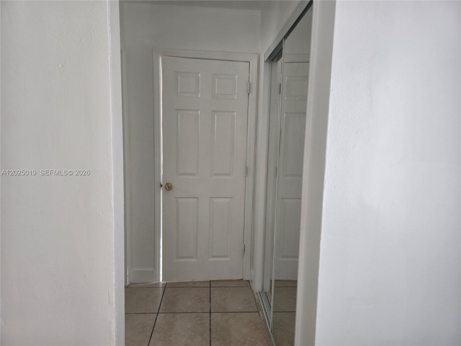 A hallway features a white six-panel door, tiled flooring, and a mirrored closet door — 408 NW 8th St # 408, Hallandale Beach FL 33009, HALLANDALE BEACH, FL