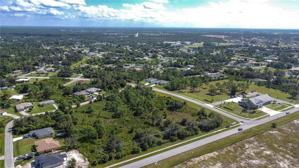 An aerial view shows a vacant, wooded lot situated near residential streets and a commercial building — 1200 N BISCAYNE DRIVE, NORTH PORT, FL