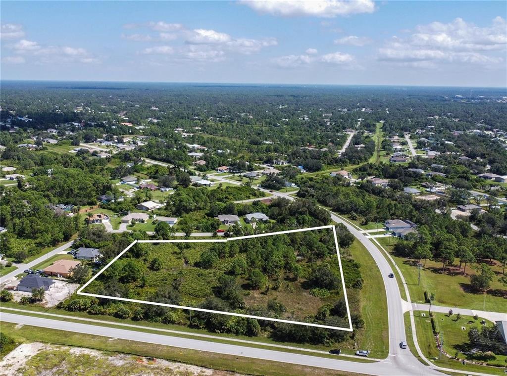 An aerial view shows a vacant, wooded lot outlined in white next to a paved road — 1200 N BISCAYNE DRIVE, NORTH PORT, FL