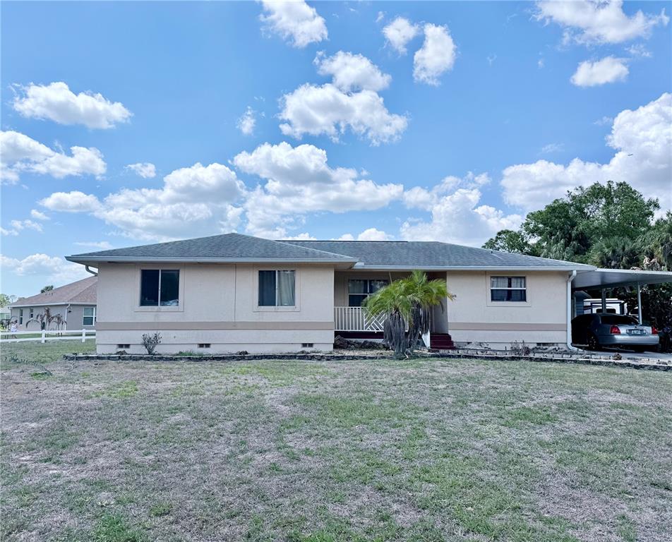 A single-story house with a beige stucco exterior, a small front porch, and gravel landscaping — 2613 VIZZA LANE, NORTH PORT, FL