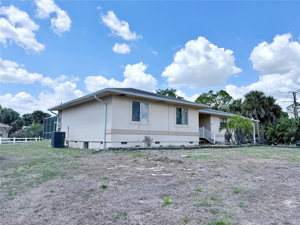 A single-story house with a beige stucco exterior, a front porch, and a concrete driveway — 2613 VIZZA LANE, NORTH PORT, FL