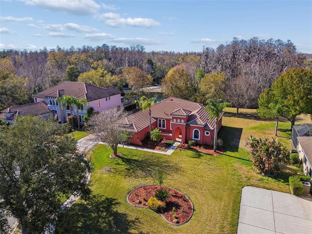 An aerial view shows a red stucco house with a tiled roof and landscaped yard — 3511 BALLASTONE DRIVE, LAND O LAKES, FL