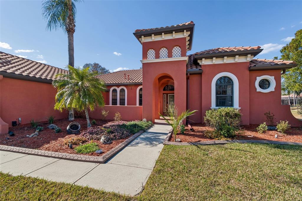 A terracotta-colored house with a tiled roof, arched windows, and a central entryway — 3511 BALLASTONE DRIVE, LAND O LAKES, FL