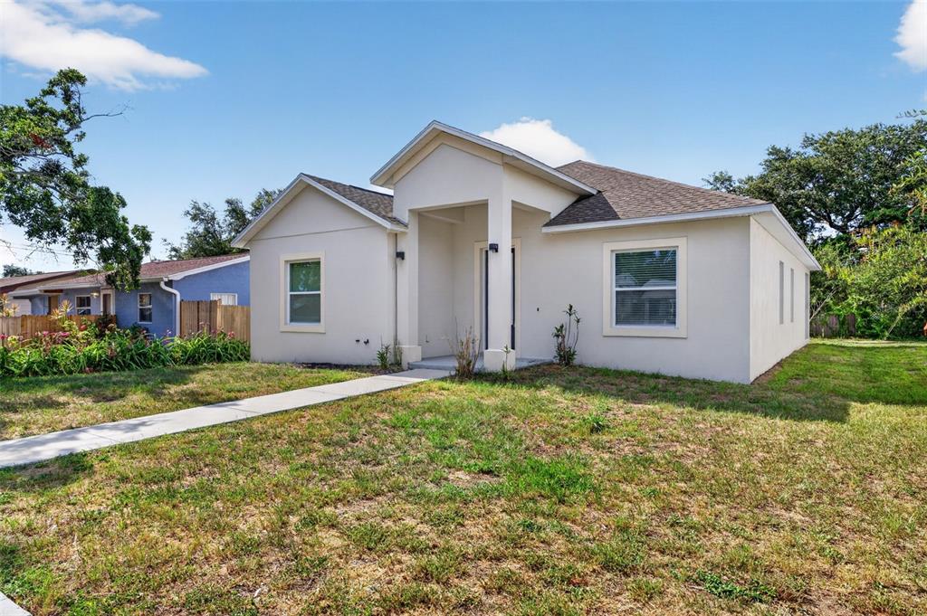 A single-story house with a light-colored stucco exterior and a covered front entryway — 7977 49TH AVENUE N, ST PETERSBURG, FL