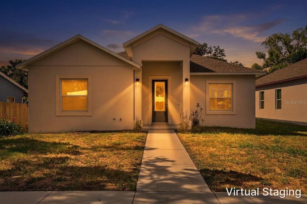 A single-story house with a beige exterior, a central entryway, and a concrete walkway at dusk — 7977 49TH AVENUE N, ST PETERSBURG, FL