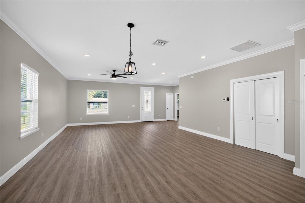 An empty living room with gray walls, wood-look flooring, recessed lighting, and a ceiling fan — 7977 49TH AVENUE N, ST PETERSBURG, FL