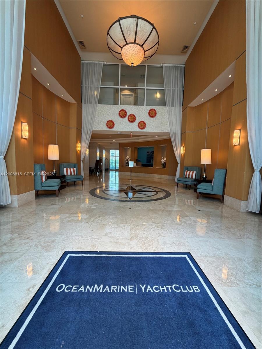 The lobby features a high ceiling, marble floors, a compass inlay, and blue accent chairs — 1945 S Ocean Dr # 603, Hallandale Beach FL 33009, HALLANDALE BEACH, FL