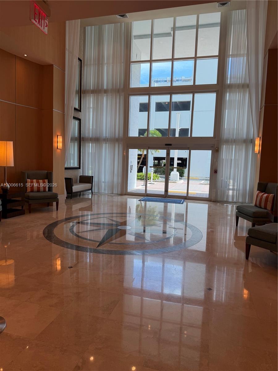 A lobby features a compass rose floor inlay, floor-to-ceiling windows, and seating areas — 1945 S Ocean Dr # 603, Hallandale Beach FL 33009, HALLANDALE BEACH, FL