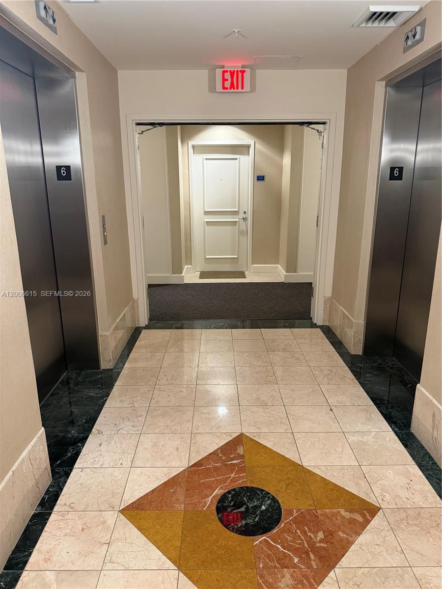 An elevator lobby features two stainless steel elevators, tiled flooring, and a central exit door — 1945 S Ocean Dr # 603, Hallandale Beach FL 33009, HALLANDALE BEACH, FL