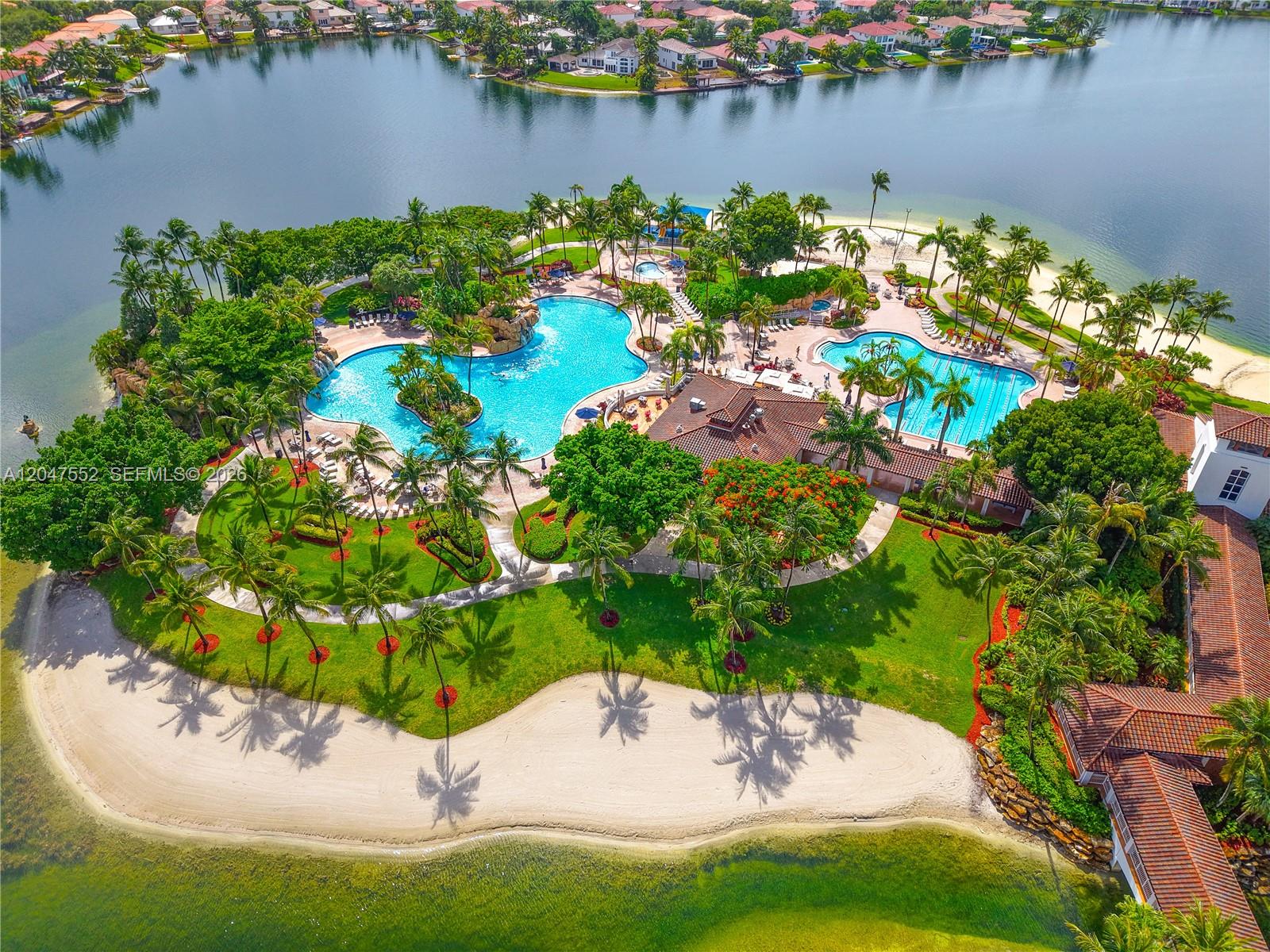 An aerial view shows a resort-style swimming pool complex surrounded by palm trees and landscaping — 10720 NW 66th St # 205, Doral FL 33178, DORAL, FL