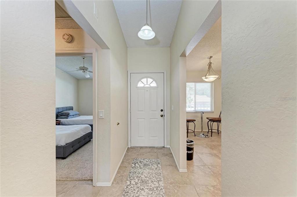 An entryway with tile flooring leads to a front door, a bedroom, and a dining area — 4366 MADEIRA COURT UNIT 3356, SARASOTA, FL