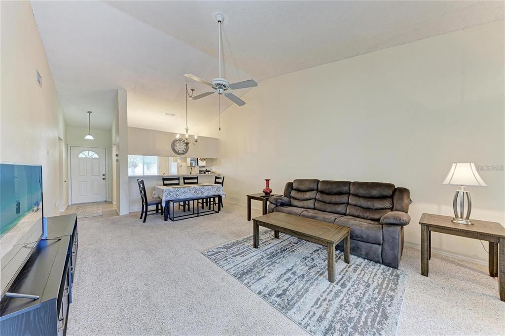 A living room with a brown sofa, coffee table, and an adjacent dining area — 4366 MADEIRA COURT UNIT 3356, SARASOTA, FL