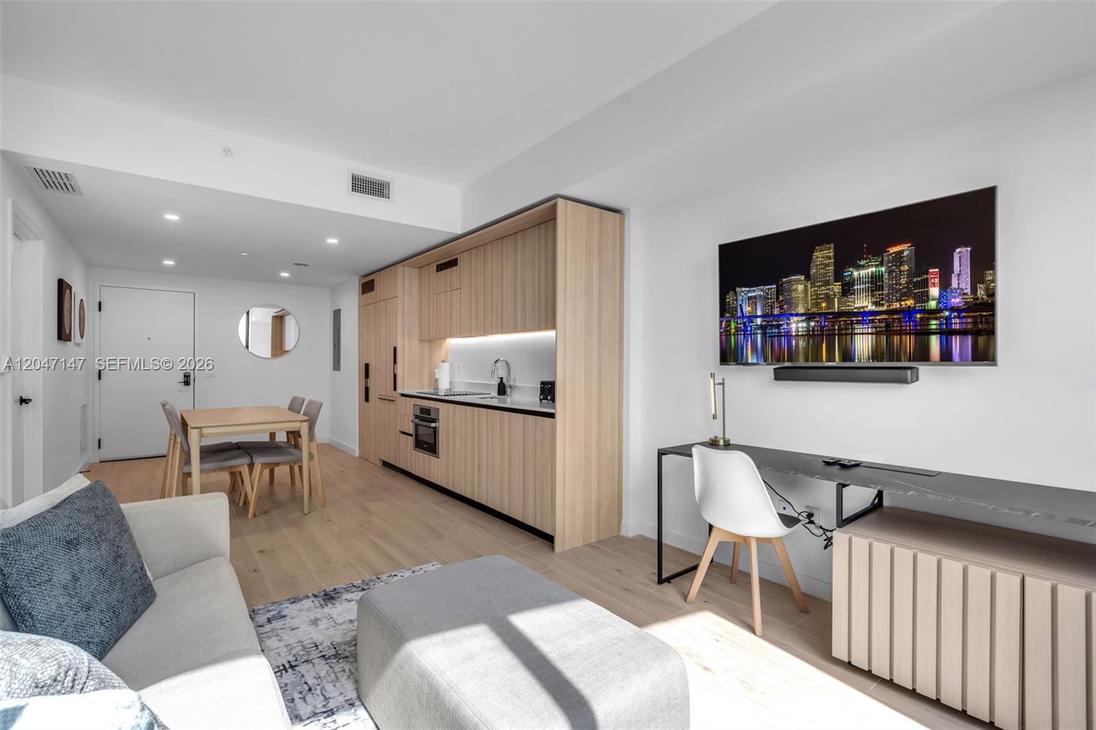 A modern studio apartment features a kitchenette, dining area, and a wall-mounted television — 225 N Miami Ave # 1107, Miami FL 33128, MIAMI, FL
