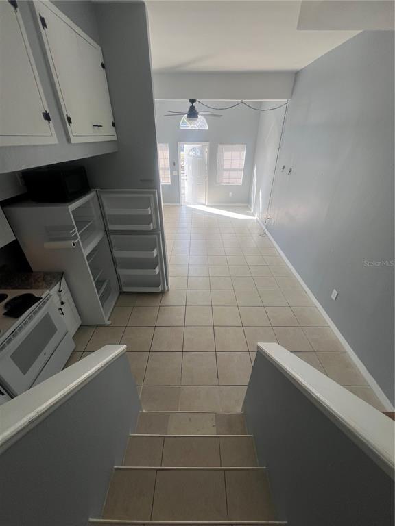 A view from a staircase looking down into a kitchen and living area with tile floors — 215 GOLDSTEIN STREET UNIT 4, PUNTA GORDA, FL