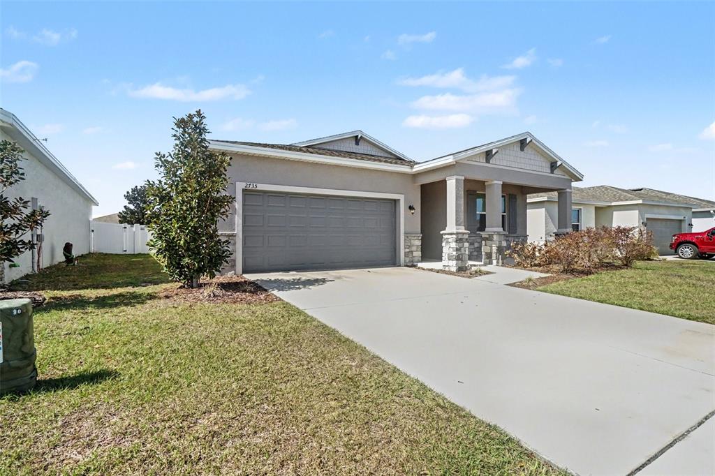 A single-story house with a gray garage, stone accents, and a covered front porch — 2735 ROWAN STREET, TAVARES, FL