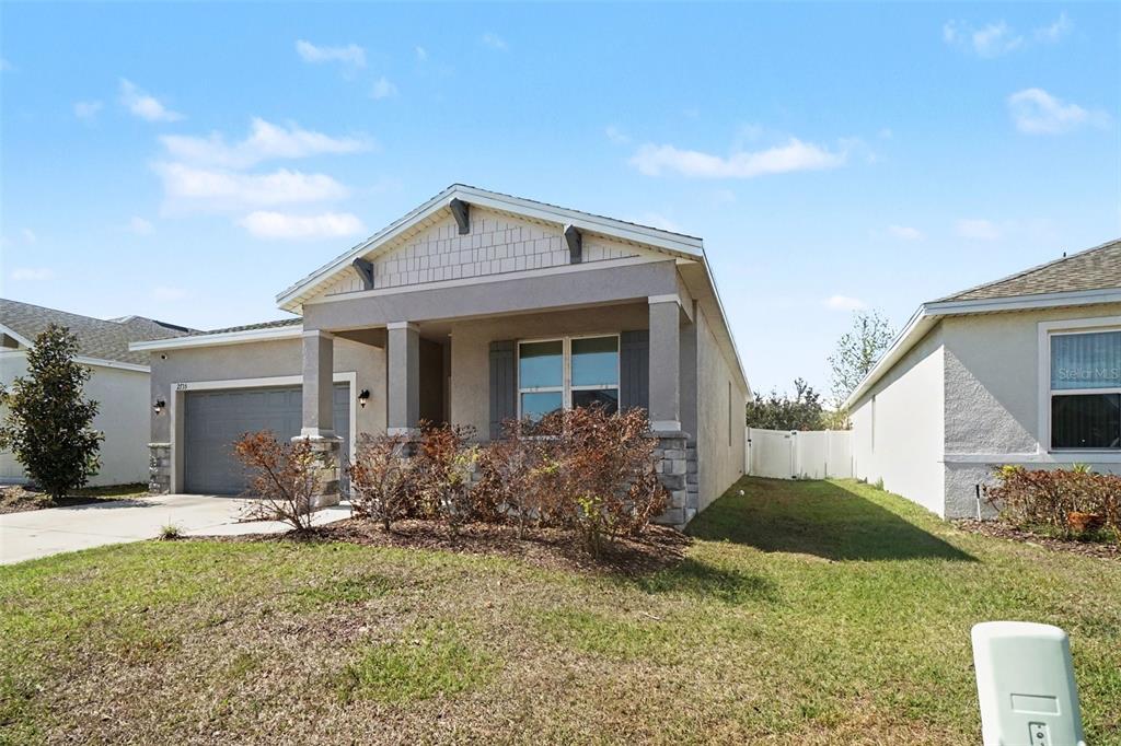A single-story suburban house with a gray garage, stone accents, and a covered front porch — 2735 ROWAN STREET, TAVARES, FL