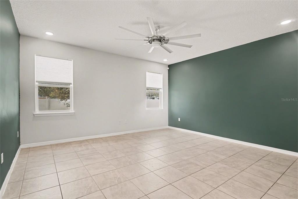 A living room features a dark green accent wall, a television console, and neutral furniture — 2735 ROWAN STREET, TAVARES, FL