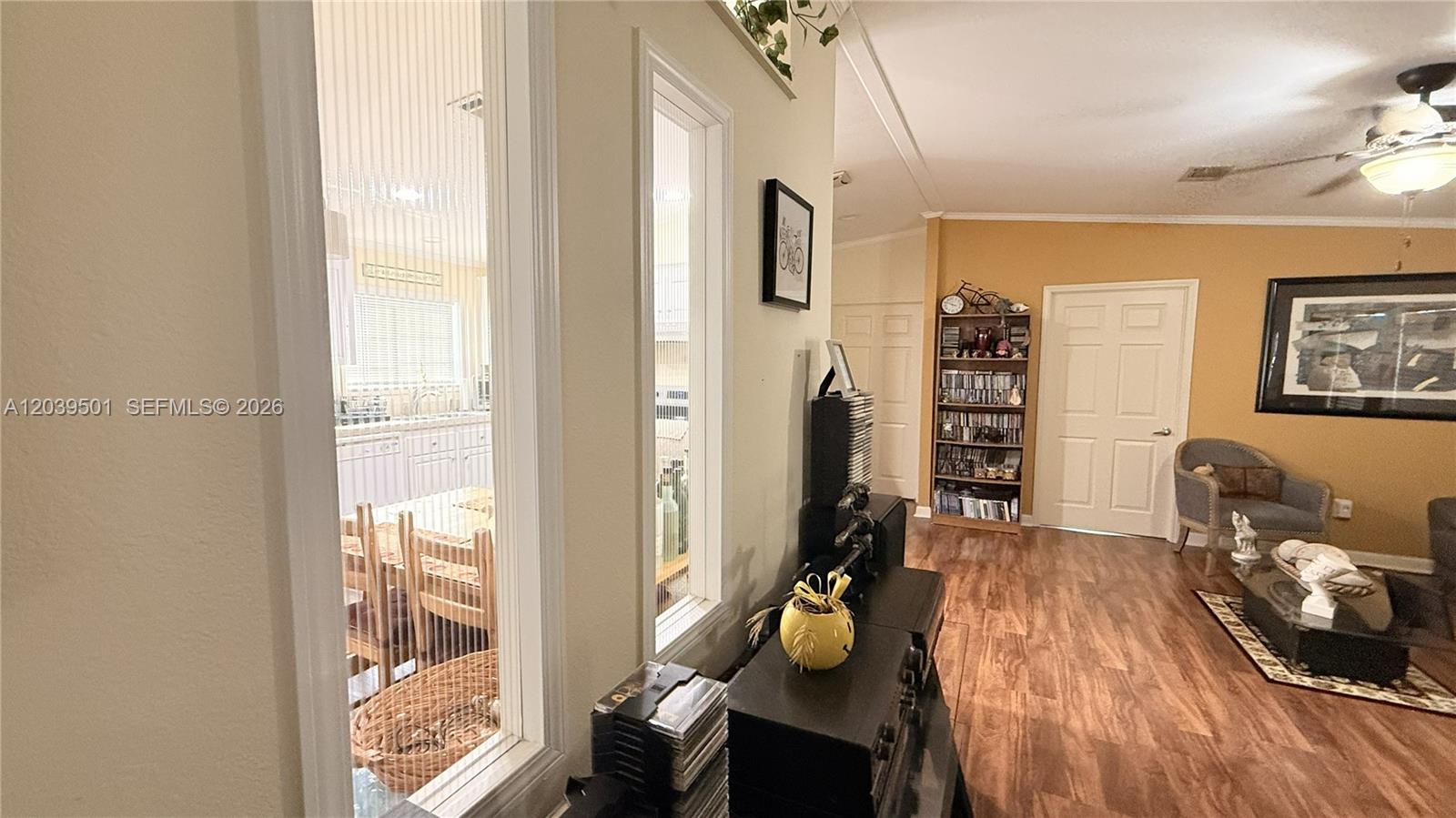 This living room features wood-look flooring, a ceiling fan, and a view into the kitchen — 8631 SW 18th Pl, Davie FL 33324, DAVIE, FL