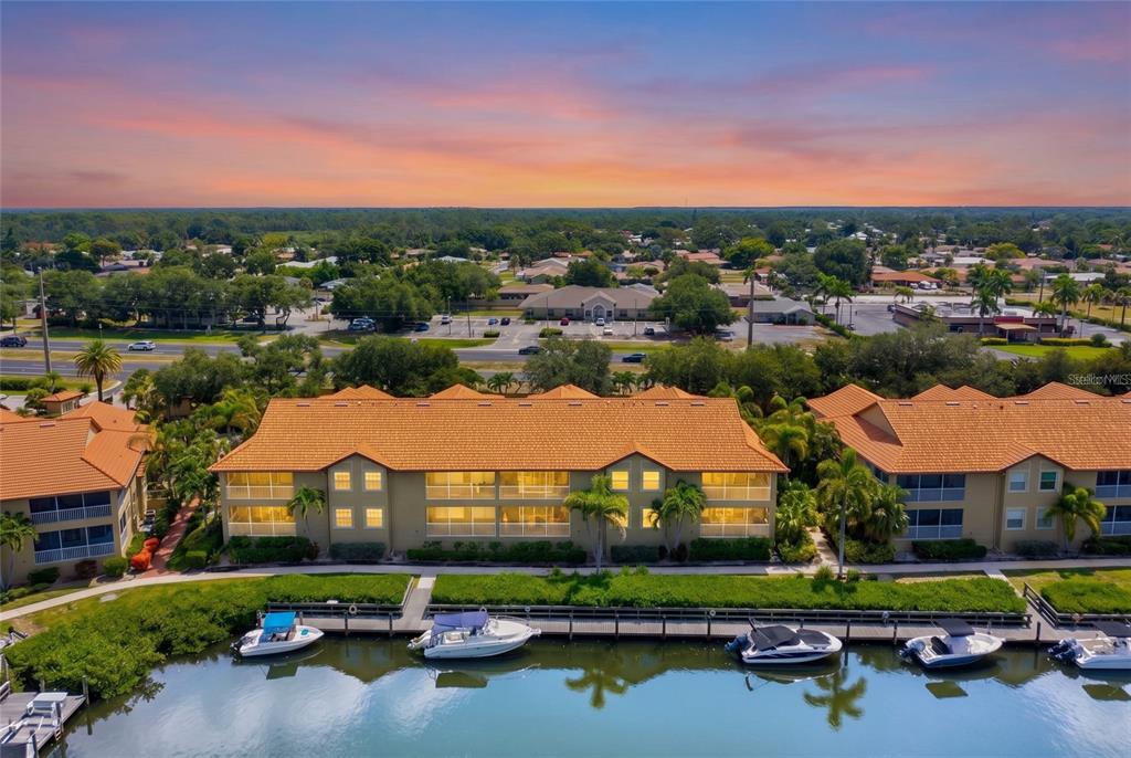 An aerial view of a multi-story apartment building with a tile roof beside a canal — 2309 JESSIE HARBOR DRIVE UNIT 2402, OSPREY, FL