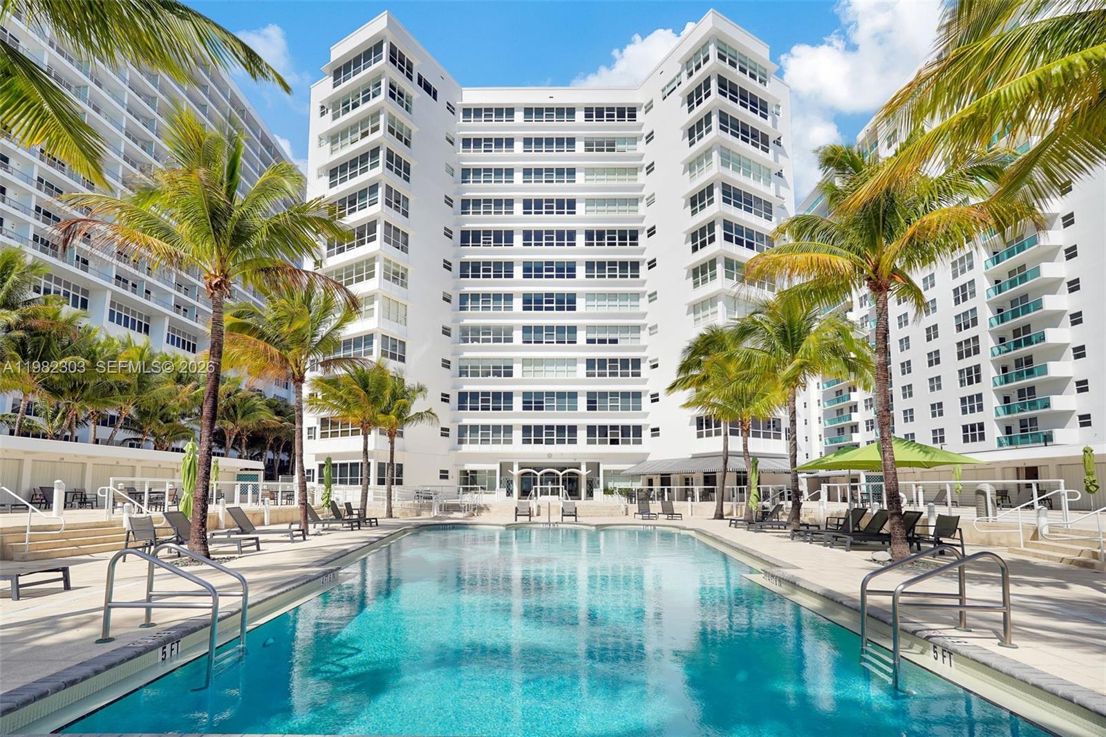 A swimming pool sits in front of a tall white residential building with palm trees — 4925 Collins Ave # 4A, Miami Beach FL 33140, MIAMI BEACH, FL