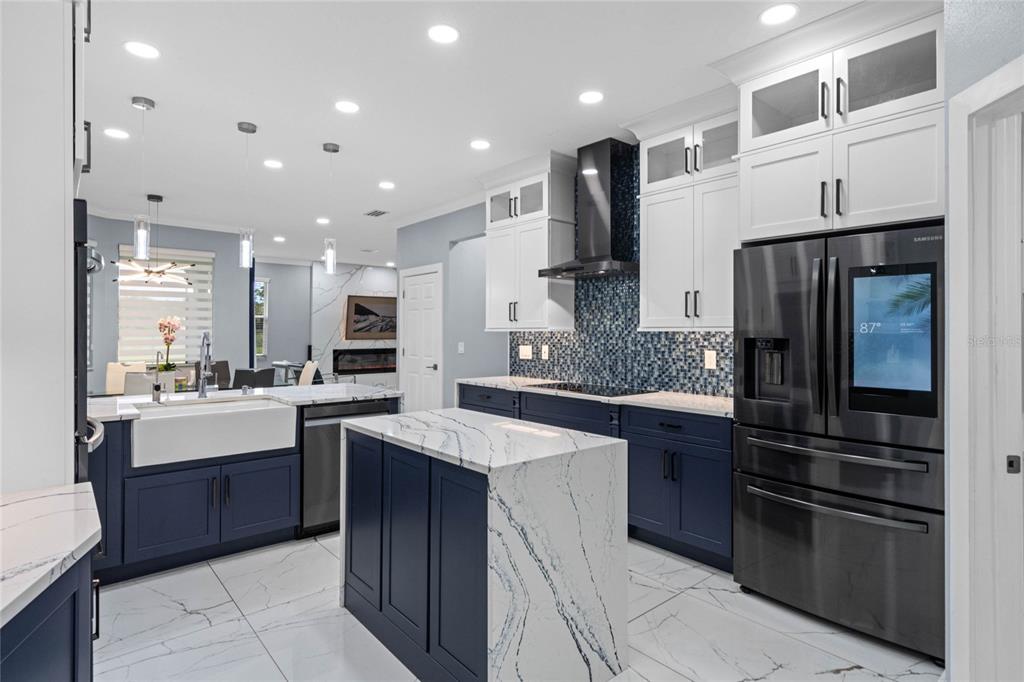 A modern kitchen features navy blue cabinetry, white marble countertops, and a blue mosaic backsplash — 6607 WHISPERING PINES ROAD, ORLANDO, FL