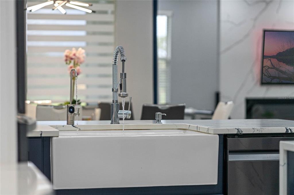 A white farmhouse sink with a chrome faucet is set into a kitchen island countertop — 6607 WHISPERING PINES ROAD, ORLANDO, FL