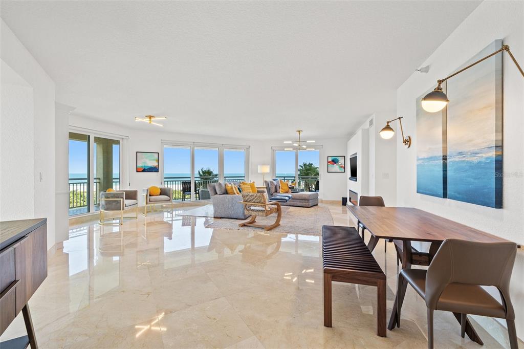 A bright, open-concept living and dining area features marble floors, modern furniture, and ocean views — 1180 GULF BOULEVARD UNIT 401, CLEARWATER BEACH, FL