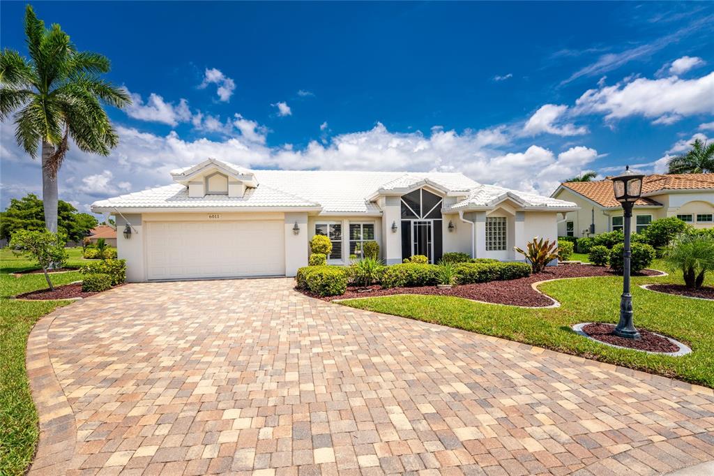 A single-story house with a white tile roof, paved driveway, and a palm tree — 6011 KEY LARGO CIRCLE, PUNTA GORDA, FL