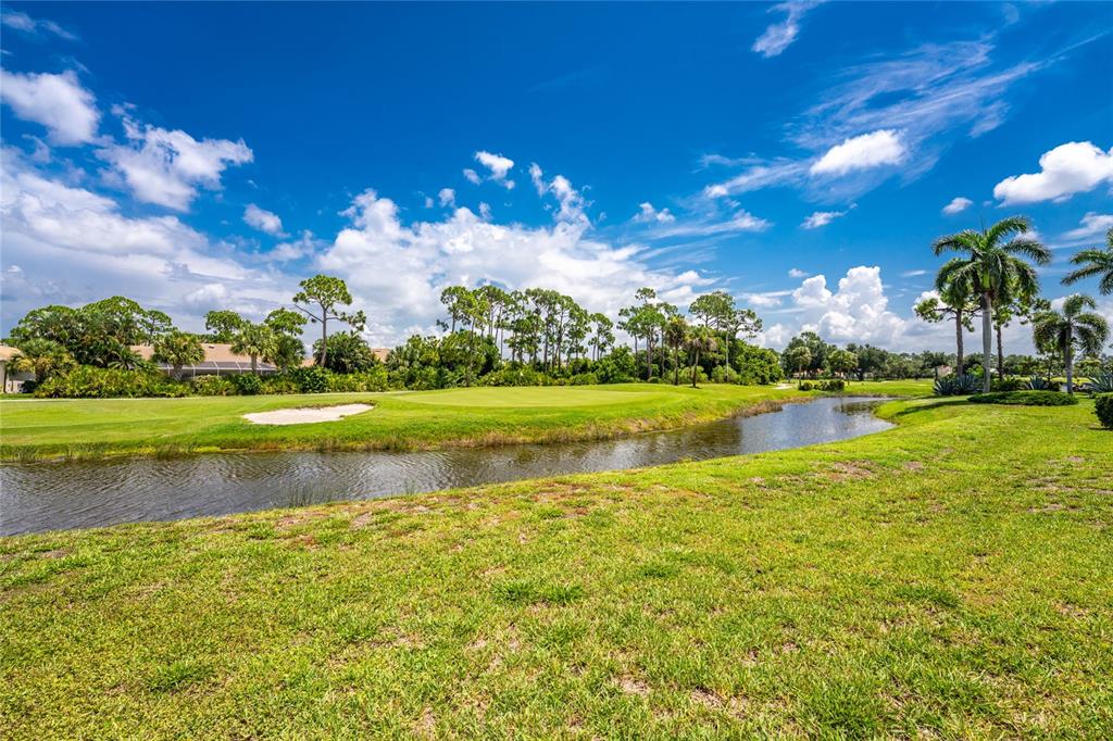 A golf course green sits beside a pond under a bright blue sky with clouds — 6011 KEY LARGO CIRCLE, PUNTA GORDA, FL