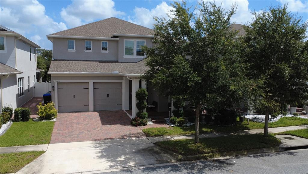 A two-story suburban house features a two-car garage, a paved driveway, and mature landscaping — 15741 SWEET LEMON WAY, WINTER GARDEN, FL