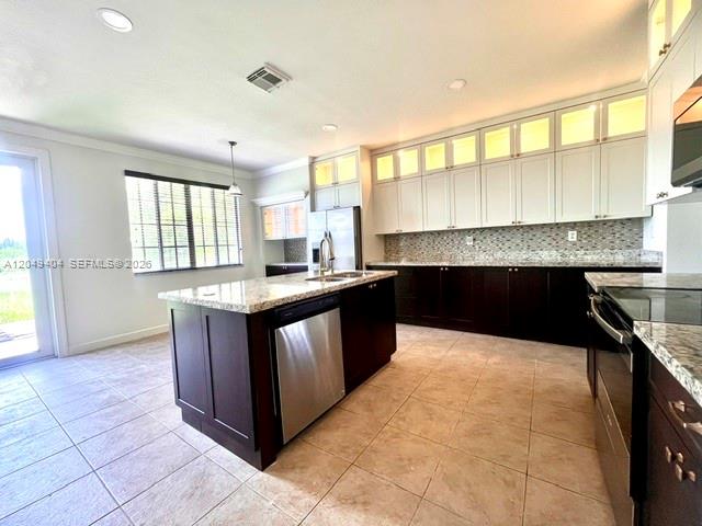 A kitchen features a dark wood island, white upper cabinets, and light-colored tile flooring — 27448 SW 143rd Ct, Homestead FL 33032, HOMESTEAD, FL