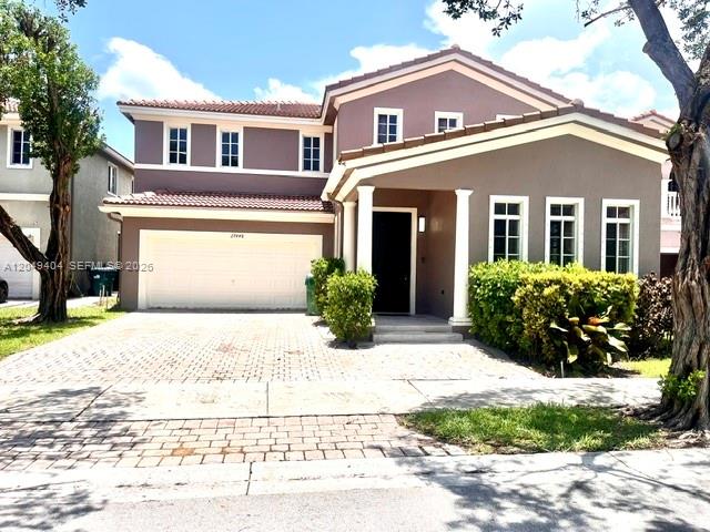 A two-story suburban house with a paved driveway, a two-car garage, and landscaped front yard — 27448 SW 143rd Ct, Homestead FL 33032, HOMESTEAD, FL